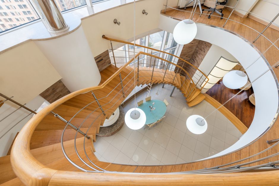 A real estate photographer with a professional camera on a tripod carefully frames a shot of a beautifully staged, high-end living room.