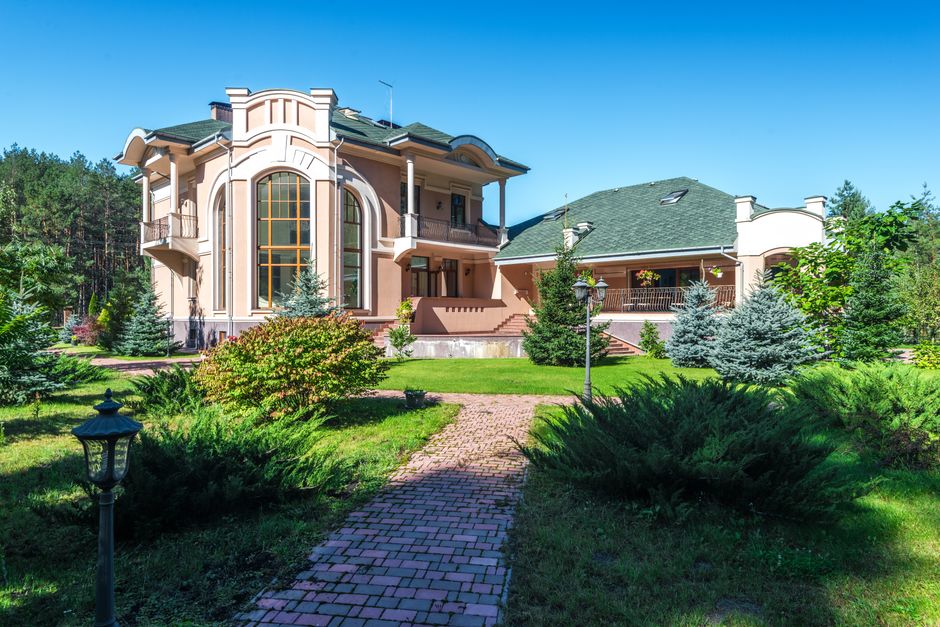 The stunning, sunlit exterior of a modern waterfront home with large glass windows, representing a perfectly marketed high-value property.