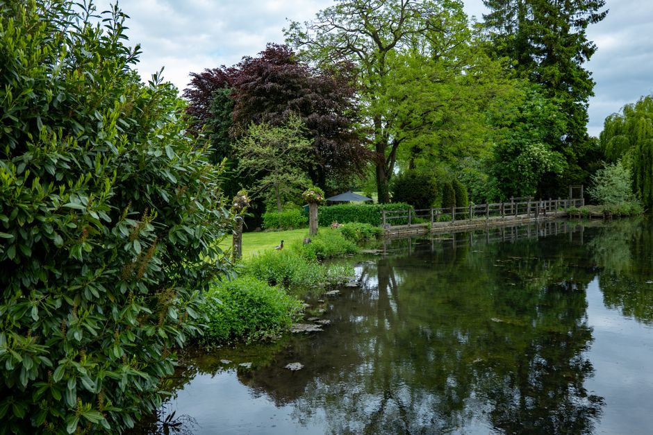 A manicured green lawn slopes gently down to meet the clear, calm water of a river, clearly defining the property's water boundary.