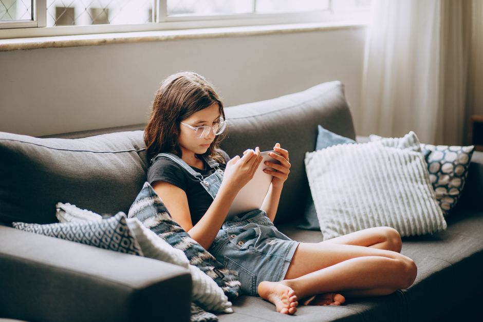A person sits comfortably in a professionally styled, bright living room, using a digital tablet to review information, symbolizing the ease of digital real estate transactions.