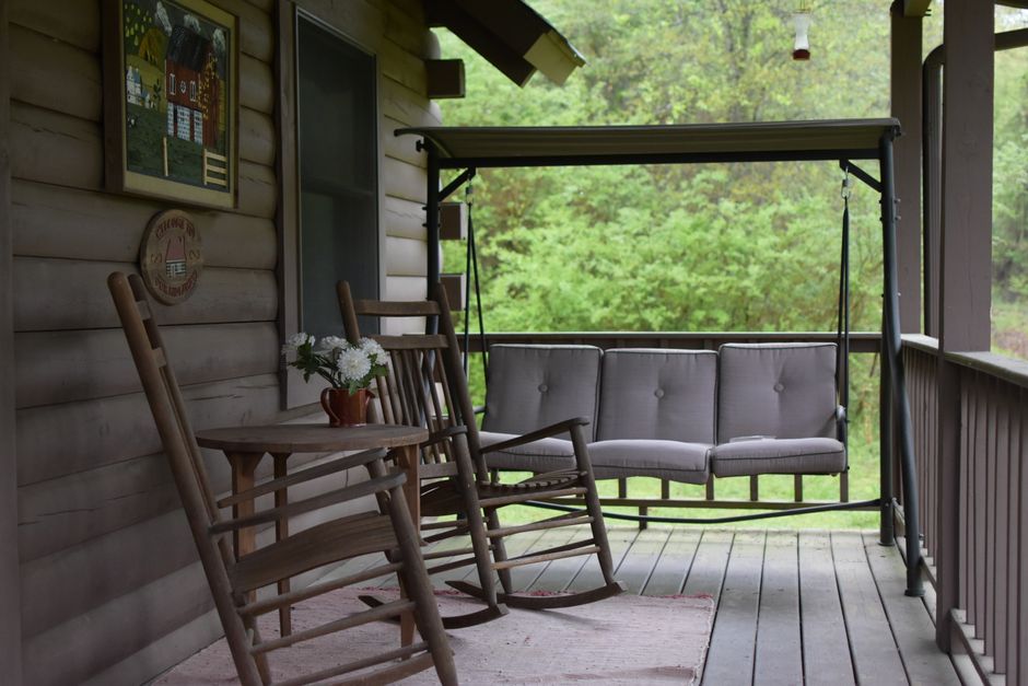 Two rocking chairs on a classic Southern porch on a hot, humid summer day, with lush, green foliage in the background, illustrating the challenge of Louisiana's climate.